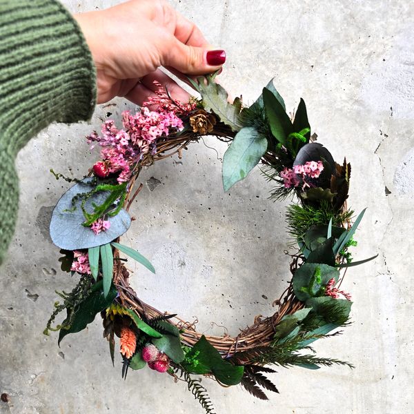 A wreath decorated with green preserved moss and plants.