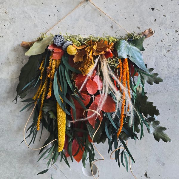 A wall hanging made of preserved plants leaves  and moss, is suspended from a natural branch
