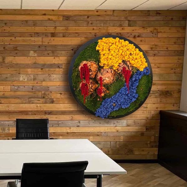 Circular piece of wall art, featuring a textured landscape crafted from preserved moss and flowers,