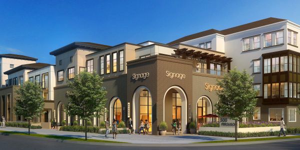 Modern mixed-use building with retail spaces and apartments under a clear blue sky.