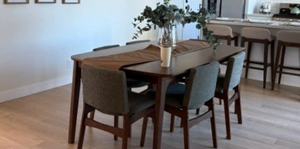 Modern dining table with four chairs and a flower vase.