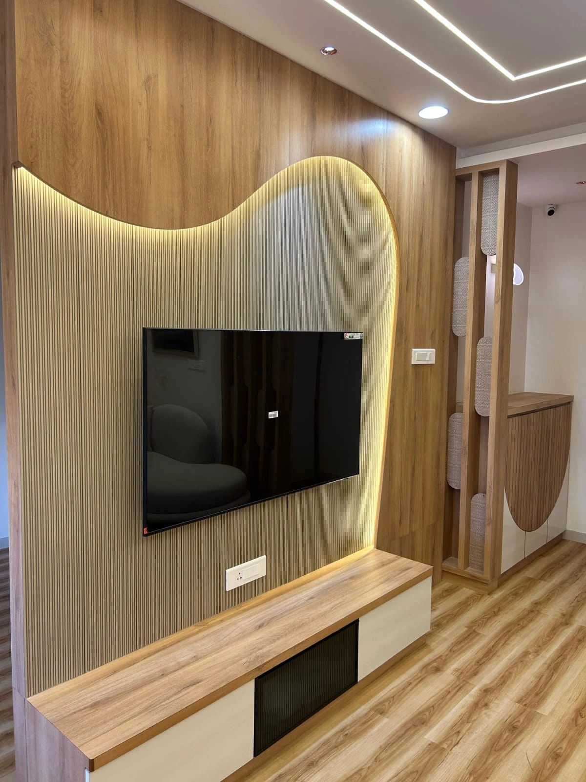 Modern living room TV wall with wood paneling and ambient lighting.