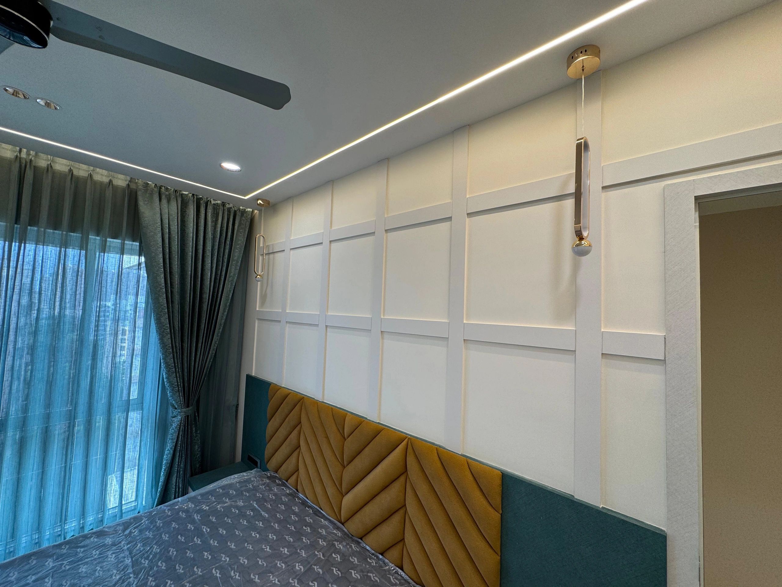 Modern bedroom with elegant lighting and textured headboard.
