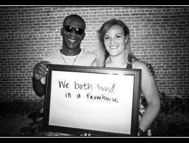 Smiling Black man, white woman hold sign: 'We both lived in a farmhouse'. photo: Douglas Vuncannon