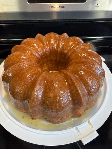 A shiny bundt cake glazed and placed on a white plate.