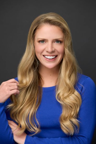 Smiling woman with long blonde hair in blue sweater.