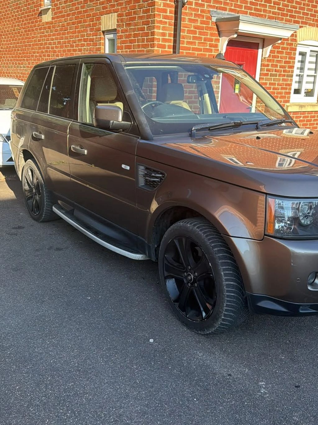 Brown SUV with black rims parked on a street.