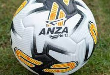 A white and black soccer ball with yellow accents lying on grass.