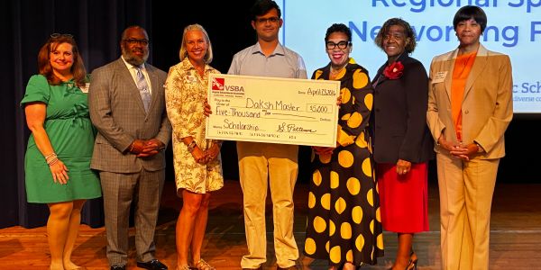 Group photo celebrating a scholarship award with a large check.
