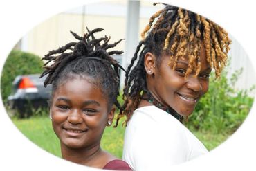 Mother and daughter with natural loc hairstyles smiling outdoors