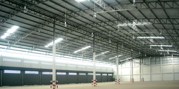 Empty large warehouse with metal roof and closed doors.