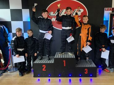 Happy young drivers on the podium after their birthday party on the petrol cadet karts