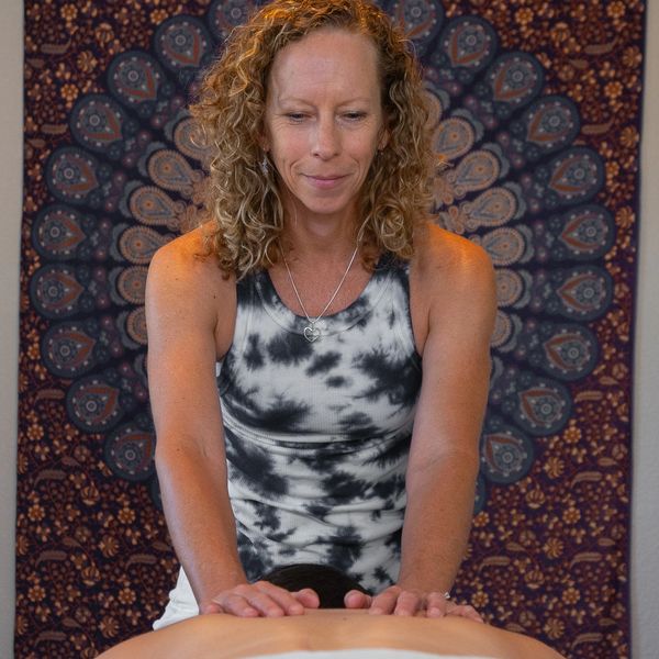 Woman giving a massage against a decorative backdrop.
