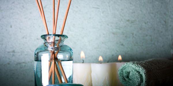 Spa candles and diffuser with towel rolled up beside next to candles