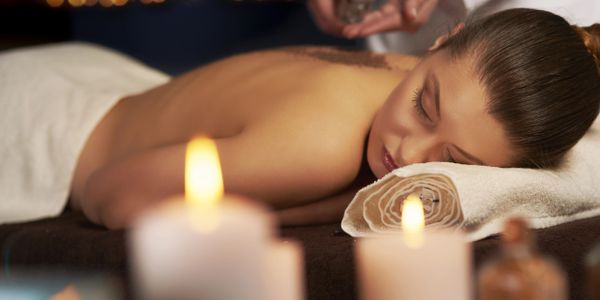 Woman relaxing during massage with candles and massage oil next to her
