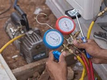 Technician adjusting HVAC manifold gauges for system pressure check.