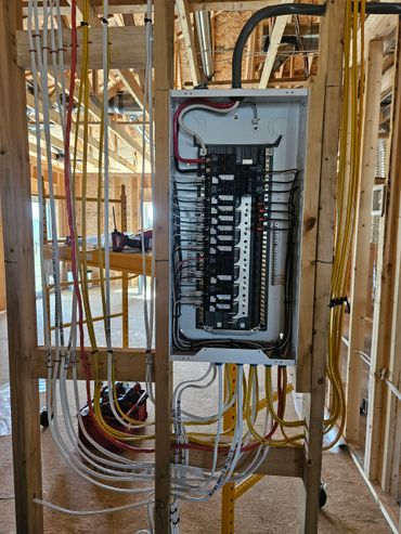 Electrical panel with organized wiring in a house under construction.