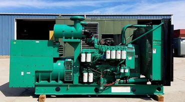 Large green industrial generator set outdoors on concrete.