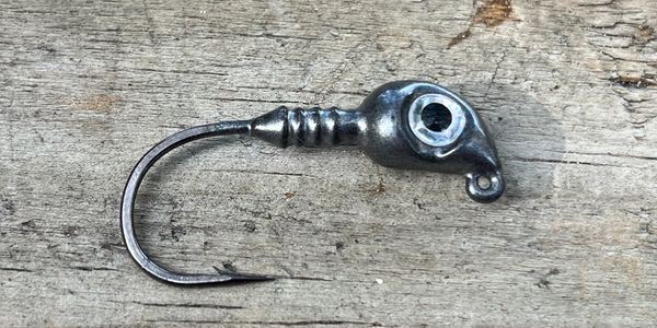 Close-up of a fishing jig head on wooden surface.