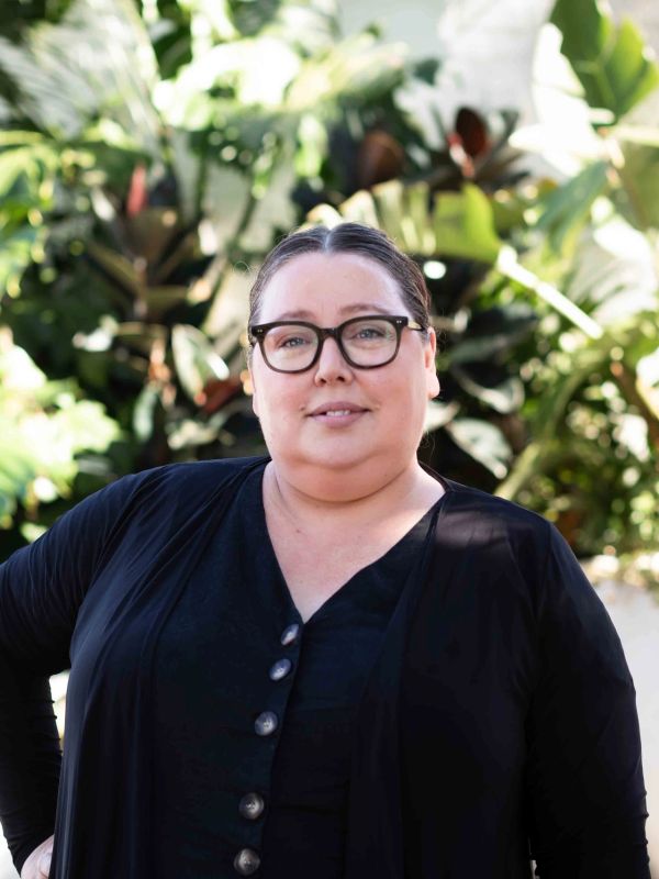 Portrait of a smiling woman with glasses outdoors.