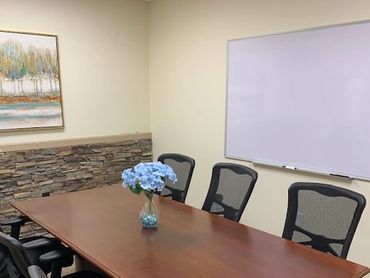 Modern conference room with wooden table, mesh chairs, and a whiteboard.