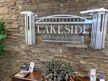 Reception area of Lakeside Executive Suites with stone wall and wooden desk.