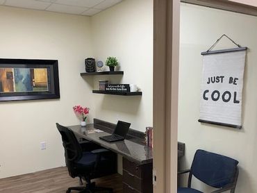 A neat, small office with a desk, chairs, and motivational decor.