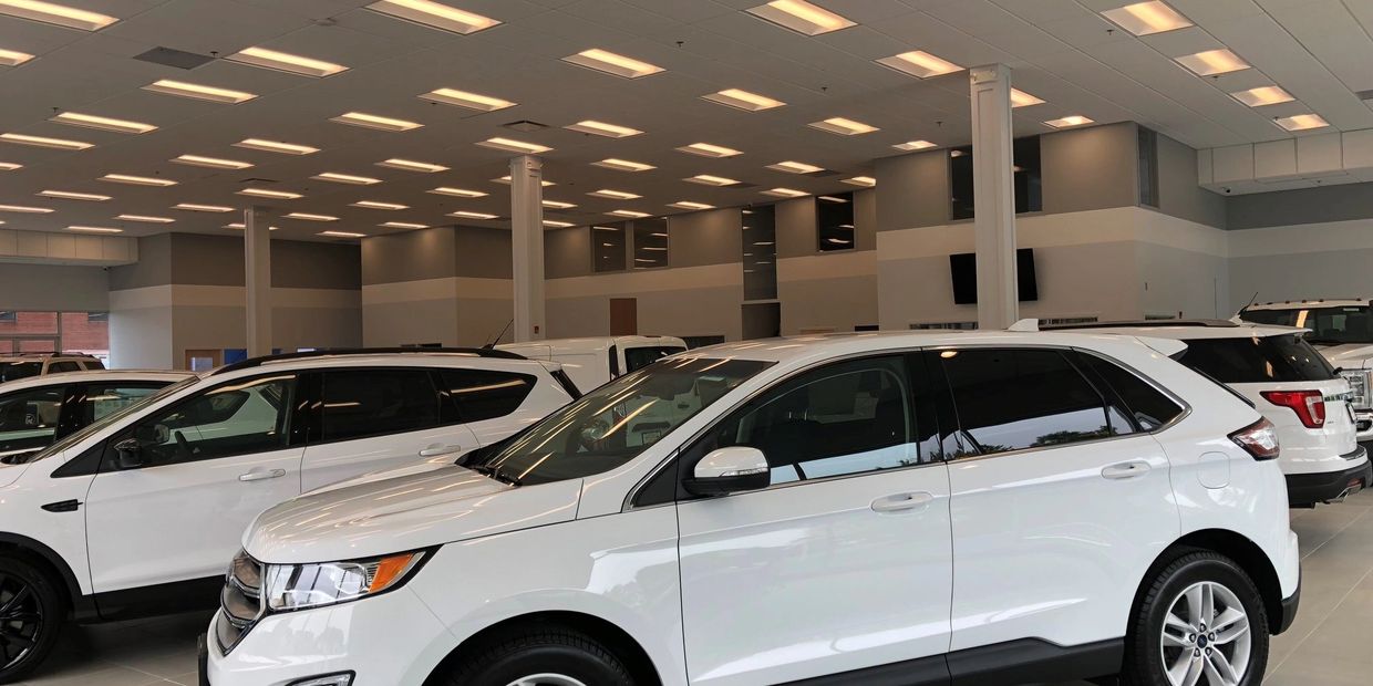 White SUVs displayed inside a well-lit car dealership showroom.