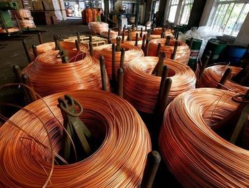 Coiled copper wire rolls stored in a warehouse with natural light.