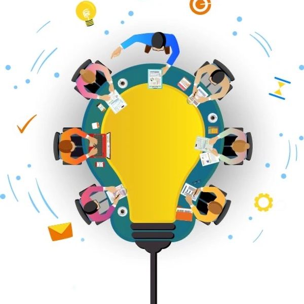 Top view of a team brainstorming around a lightbulb-shaped table symbolizing ideas.