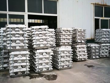 Stacks of metal ingots outside an industrial building.