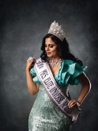 Woman wearing a crown and sash posing confidently.