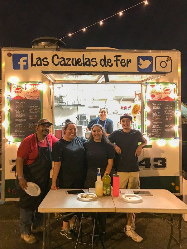 The Antunez family posing in front of the food truck at night.