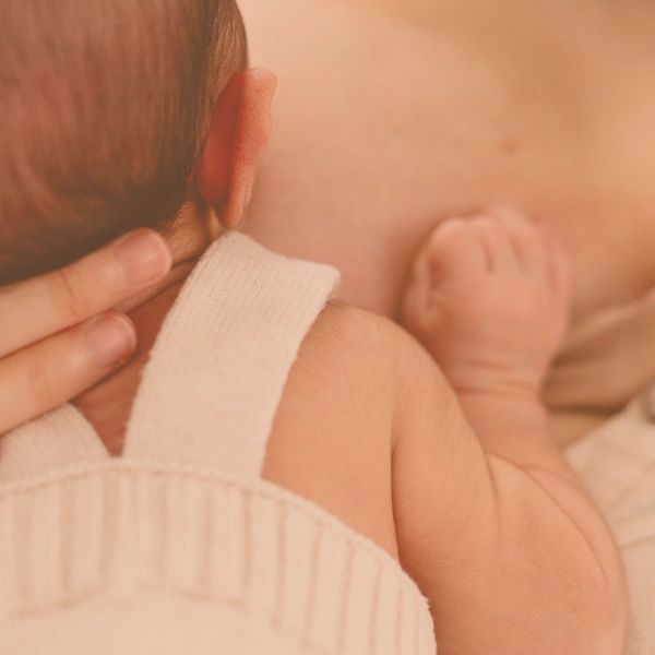 Close-up of a baby resting on an adult's chest.