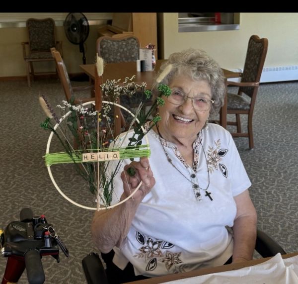 Elderly woman showing off her decorative hoop she designed with the word "hello" on it