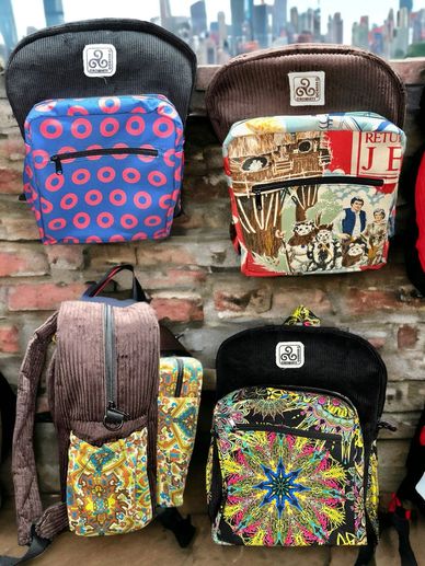 4 backpacks one each phish, star wars, trippy mandala and vintage fabric with a brick background