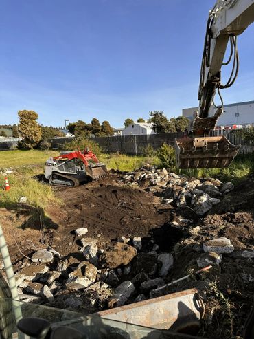 Construction site with excavators and rubble under a clear blue sky.