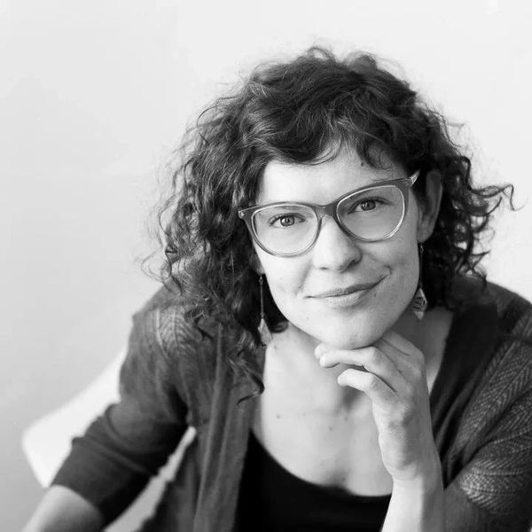 Woman with glasses smiling gently at the camera.