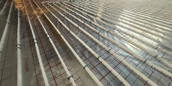 Underfloor heating pipes installed on a reflective insulation layer in a construction site.