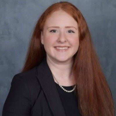 Professional portrait of a smiling woman with long red hair.