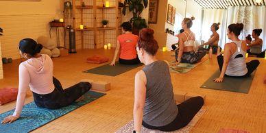 Group yoga session in a cozy, candle-lit studio with mirrors and calming decor. Jenny Von Jenny Well