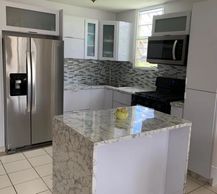 Cocina blanca en PVC a la medida con cascadas pvc carrara. Construida en Puerto Rico.