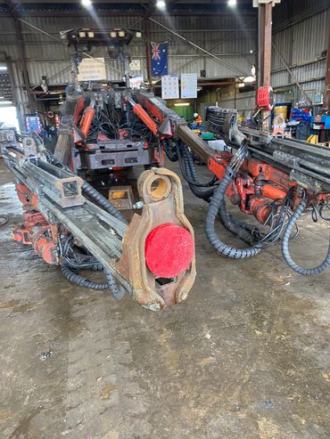 Heavy industrial machinery with hydraulic arms inside a workshop.