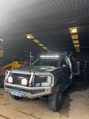 A rugged Ford pickup truck with off-road lights inside a garage.
