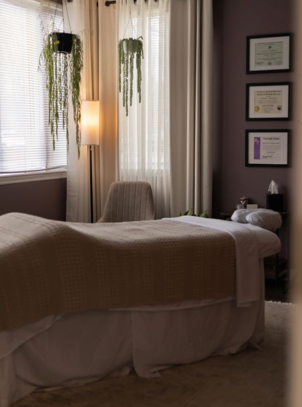 Cozy therapy or massage room with a bed and hanging plants.
