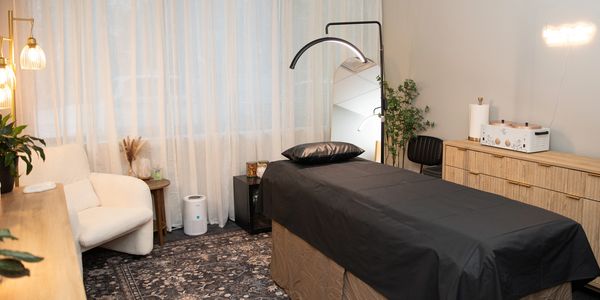 Cozy massage room with black-covered table and soft lighting.