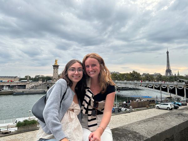 Two women smiling near the Eiffel Tower in Paris.