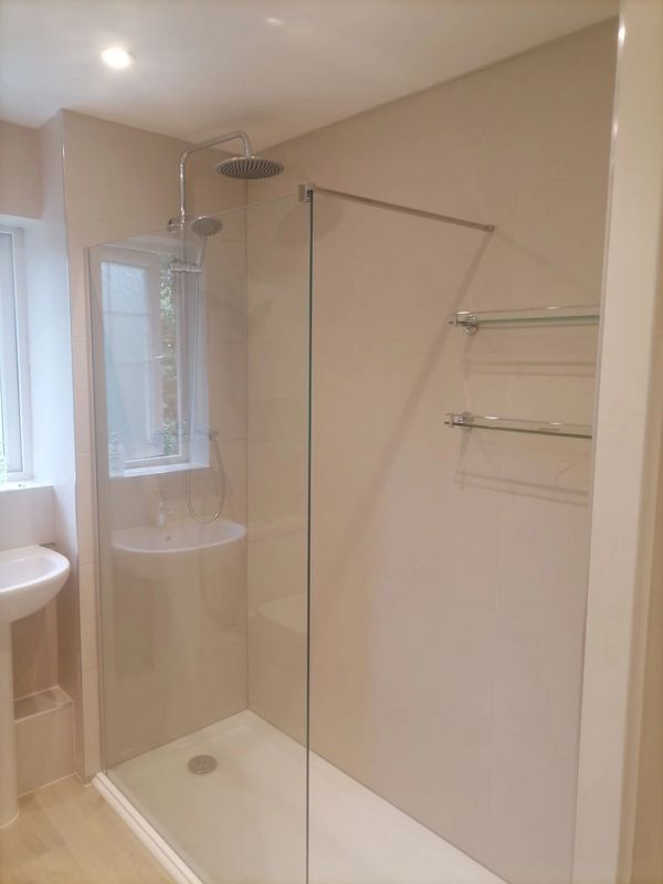 Premium walk-in shower by skilled bathroom fitter. Glass shelves and concealed shower valves.