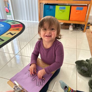 A little girl smiling and drawing