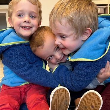 Three boys smiling and hugging